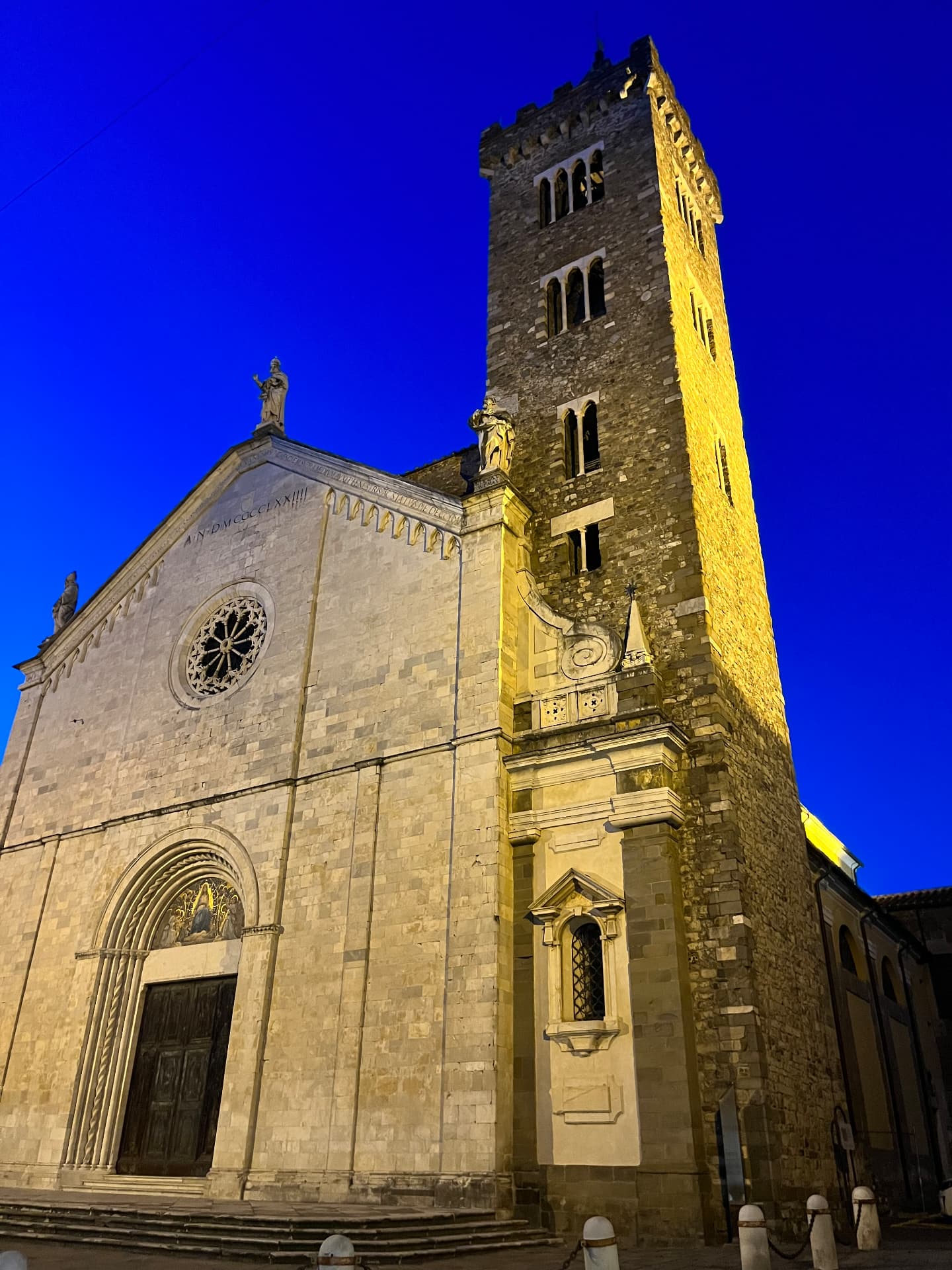 A cathedral facade and bell tower lit up at dusk